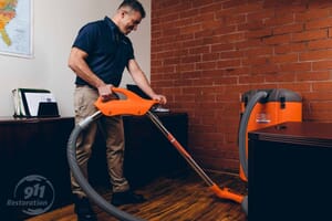 commercial restoration technician vacuuming water from office