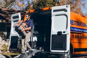 water damage restoration technician taking equipment out of vehicle